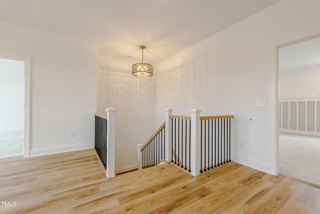 empty room featuring a chandelier, baseboards, and wood finished floors