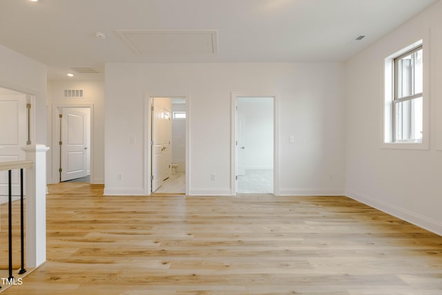 unfurnished bedroom with visible vents, ensuite bath, light wood finished floors, baseboards, and attic access