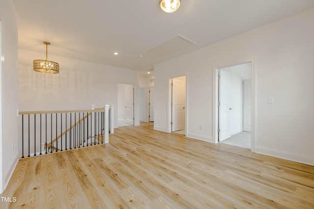 spare room with recessed lighting, attic access, baseboards, and wood finished floors