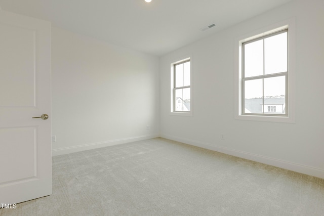 empty room with visible vents, baseboards, and light colored carpet