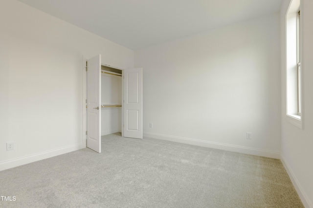 unfurnished bedroom featuring baseboards, a closet, and light carpet