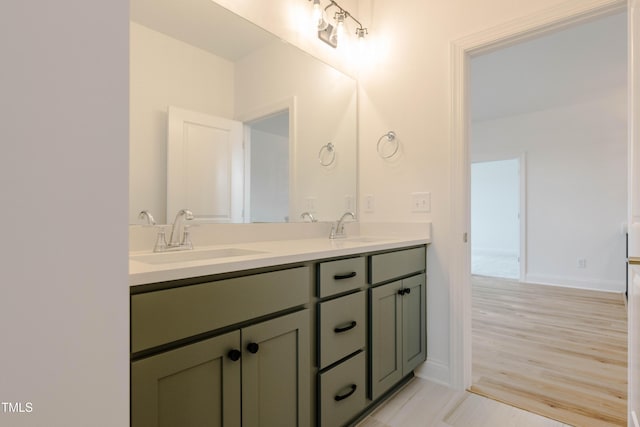 full bathroom featuring double vanity, wood finished floors, baseboards, and a sink