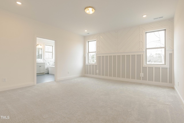 empty room with carpet flooring, recessed lighting, baseboards, and visible vents