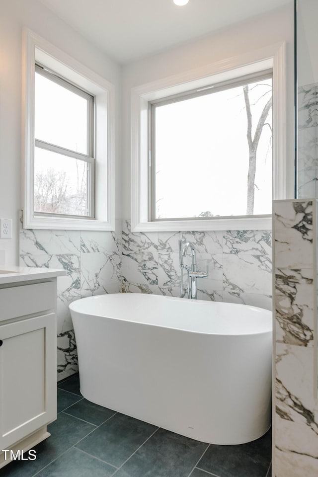 bathroom featuring a freestanding tub, tile walls, vanity, and tile patterned flooring