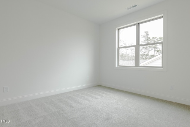 spare room with visible vents, baseboards, and light colored carpet