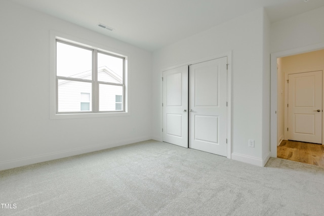 unfurnished bedroom featuring carpet flooring, baseboards, visible vents, and a closet