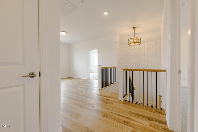 hall featuring an upstairs landing, attic access, and wood finished floors