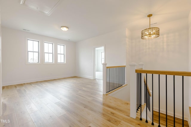 spare room with baseboards, attic access, and wood finished floors