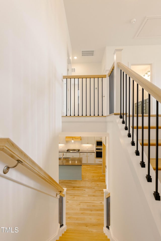 stairs featuring wood finished floors and visible vents