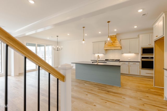 kitchen featuring oven, premium range hood, light wood-style flooring, a sink, and stovetop