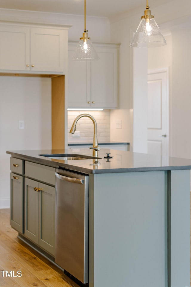 kitchen featuring a center island with sink, dishwasher, pendant lighting, decorative backsplash, and a sink