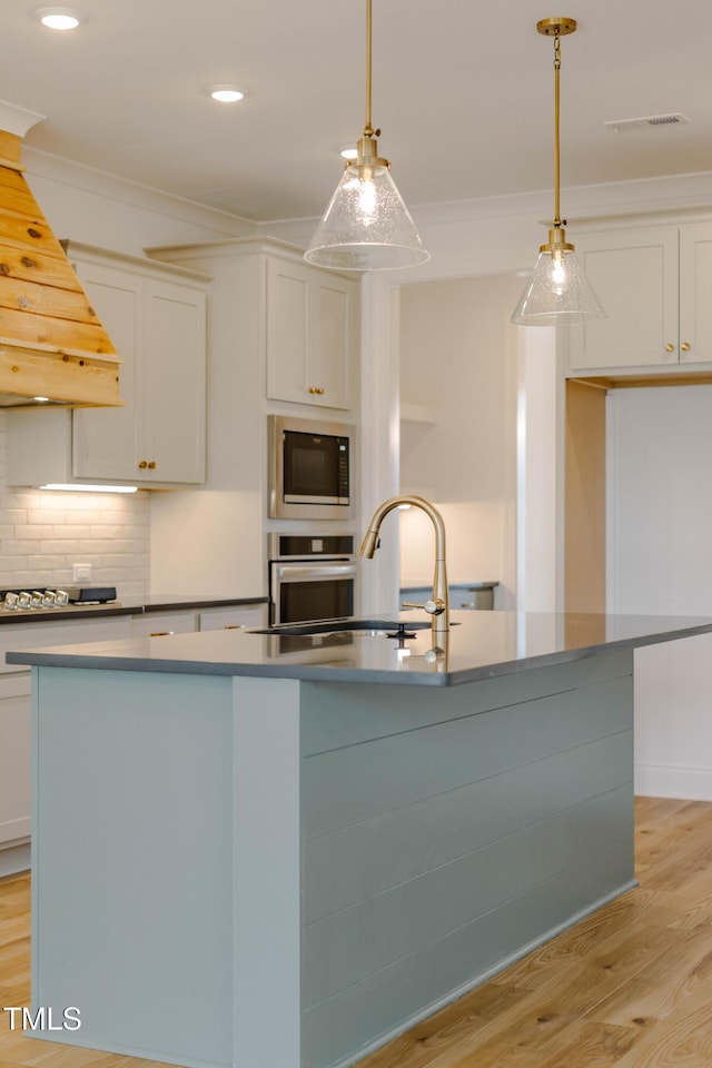 kitchen featuring oven, visible vents, a sink, built in microwave, and custom exhaust hood