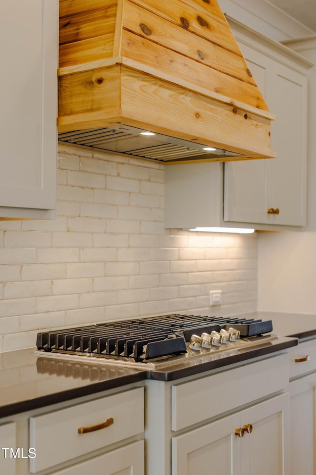 kitchen with dark countertops, decorative backsplash, white cabinetry, and premium range hood