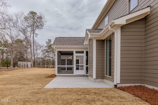 entrance to property with a yard, a patio area, and a shingled roof