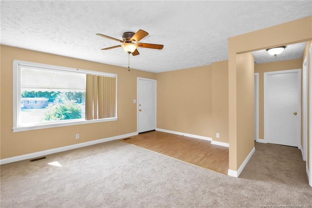 spare room featuring light colored carpet, ceiling fan, and a textured ceiling