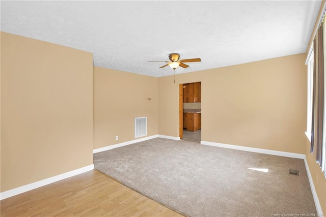 carpeted spare room with ceiling fan and a textured ceiling