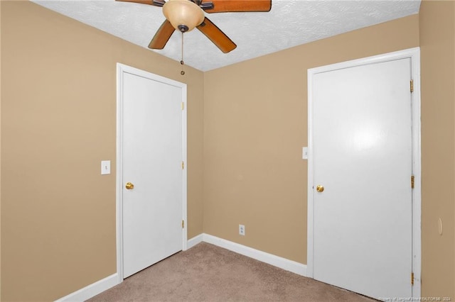 unfurnished room with a textured ceiling, ceiling fan, and light carpet