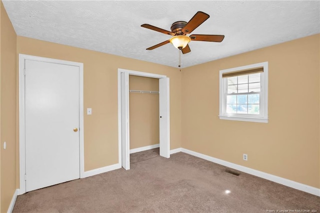 unfurnished bedroom with a textured ceiling, light colored carpet, ceiling fan, and a closet