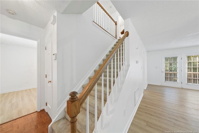 stairway featuring hardwood / wood-style flooring and a textured ceiling