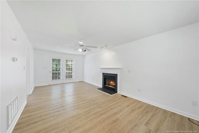 unfurnished living room with a textured ceiling, light hardwood / wood-style flooring, ceiling fan, and rail lighting