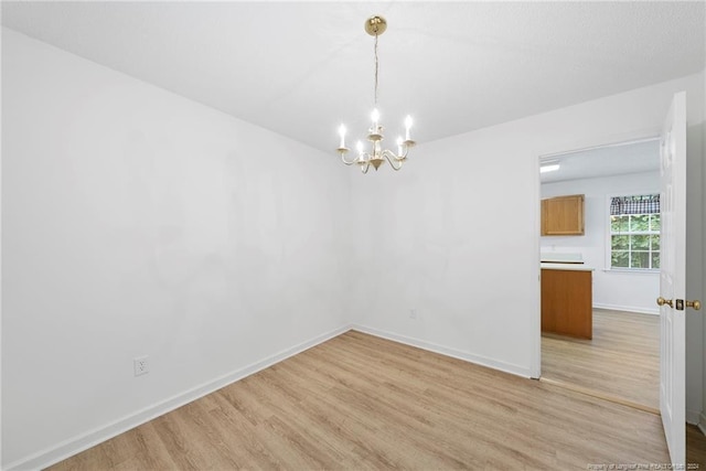 unfurnished dining area featuring light wood-type flooring and an inviting chandelier