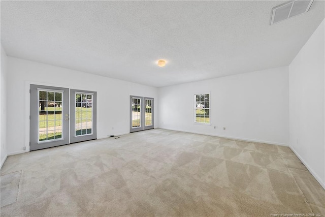 carpeted empty room featuring a textured ceiling and french doors