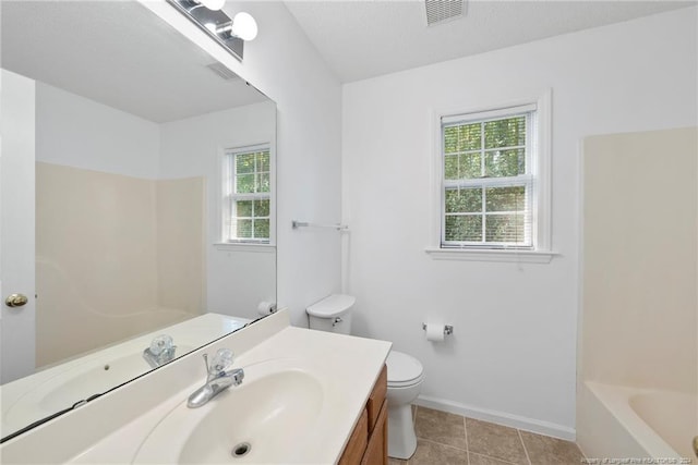 bathroom with vanity, toilet, a wealth of natural light, and tile patterned flooring