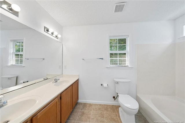 bathroom with vanity, toilet, a wealth of natural light, and a textured ceiling