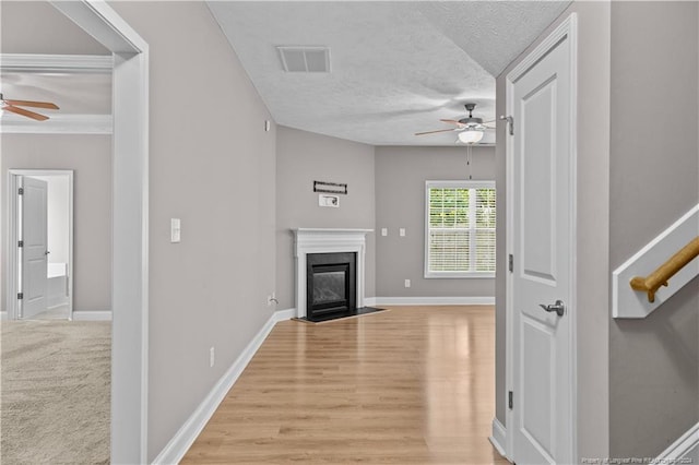 unfurnished living room featuring ceiling fan, hardwood / wood-style flooring, a high end fireplace, and a textured ceiling