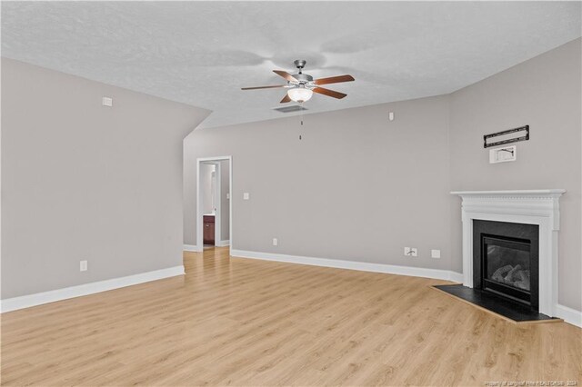 unfurnished living room featuring hardwood / wood-style floors, ceiling fan, and a textured ceiling