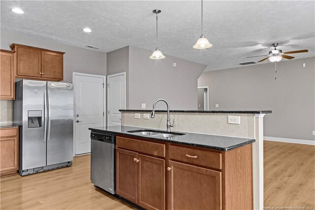 kitchen featuring a kitchen island with sink, stainless steel appliances, sink, decorative backsplash, and ceiling fan