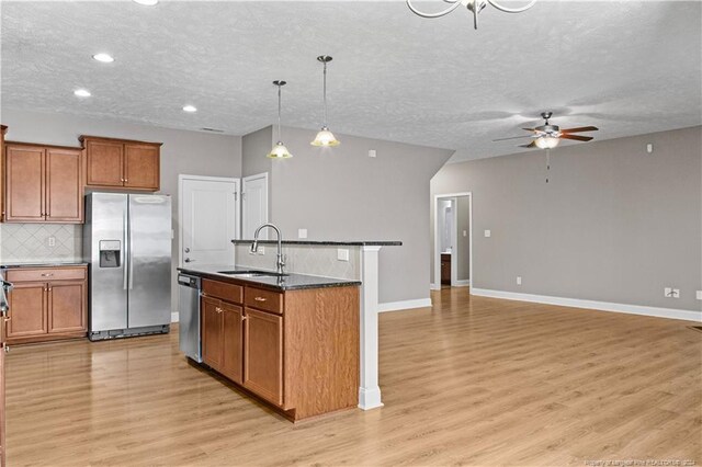 kitchen featuring hanging light fixtures, appliances with stainless steel finishes, sink, ceiling fan, and a kitchen island with sink