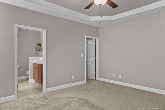 unfurnished bedroom with light colored carpet, connected bathroom, ceiling fan, and a tray ceiling