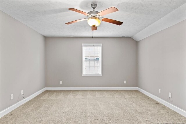 carpeted spare room featuring lofted ceiling, ceiling fan, and a textured ceiling