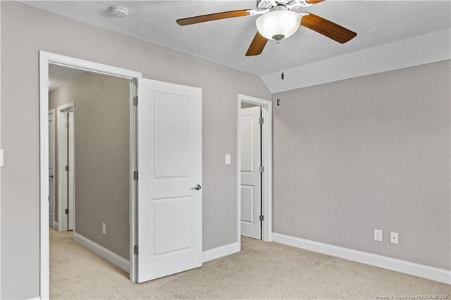 unfurnished bedroom featuring light carpet, vaulted ceiling, and ceiling fan