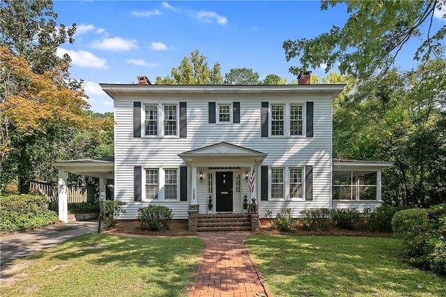 colonial inspired home featuring a front lawn and a carport