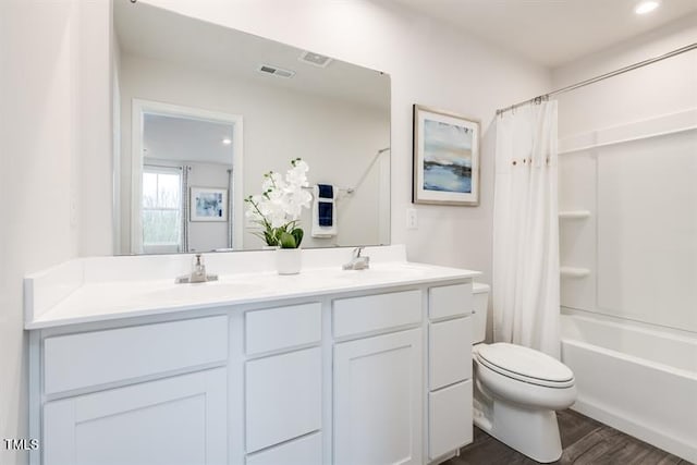 full bathroom featuring hardwood / wood-style flooring, shower / tub combo with curtain, vanity, and toilet