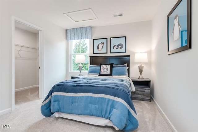 bedroom with a walk in closet and light carpet