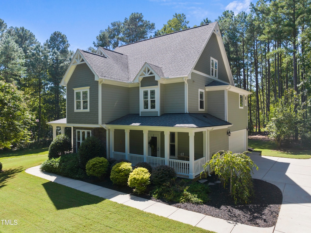 view of front of home with a garage, covered porch, and a front lawn