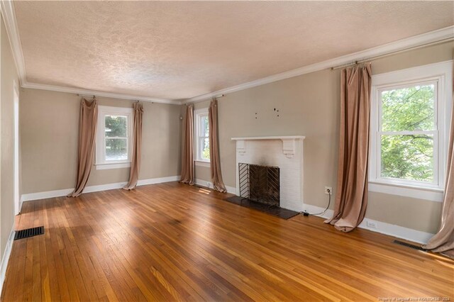 unfurnished living room with a fireplace, hardwood / wood-style flooring, a textured ceiling, and a wealth of natural light