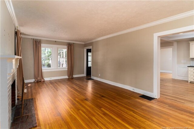 unfurnished living room featuring a textured ceiling, ornamental molding, hardwood / wood-style floors, and a fireplace