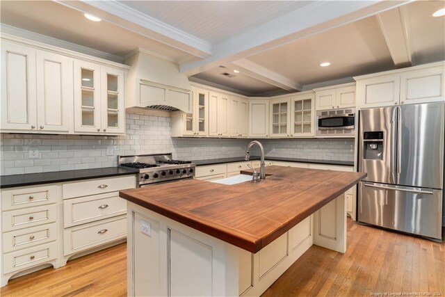 kitchen featuring a center island with sink, stainless steel appliances, beam ceiling, and sink