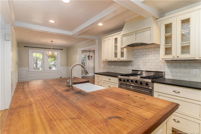 kitchen featuring high end stainless steel range, crown molding, sink, hanging light fixtures, and light hardwood / wood-style floors