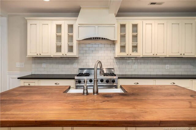 kitchen with premium range hood, backsplash, crown molding, and high end stainless steel range