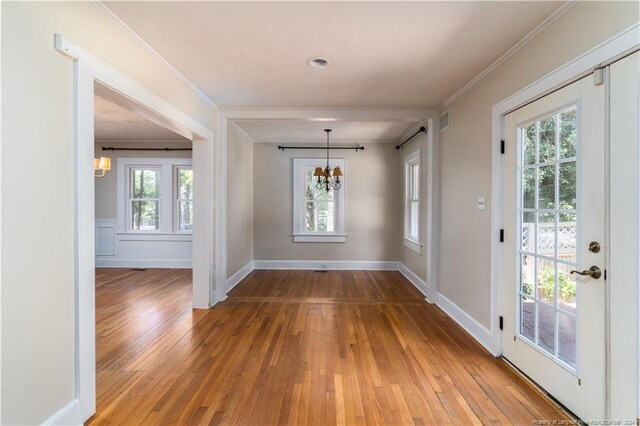 interior space featuring hardwood / wood-style floors, a wealth of natural light, an inviting chandelier, and crown molding