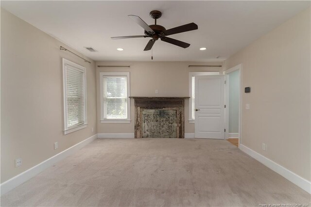 unfurnished living room featuring light colored carpet, ceiling fan, and a fireplace