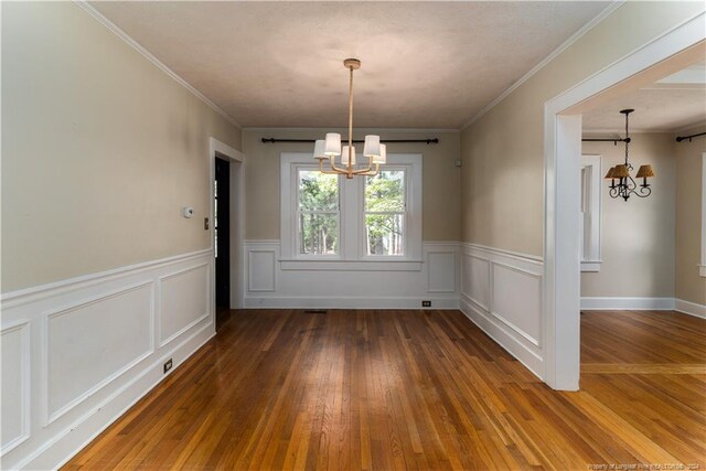 unfurnished dining area with dark hardwood / wood-style floors, an inviting chandelier, and crown molding