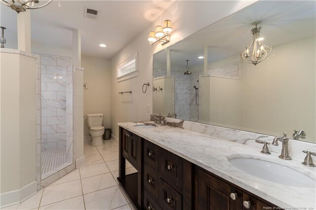 bathroom featuring toilet, a tile shower, an inviting chandelier, and vanity