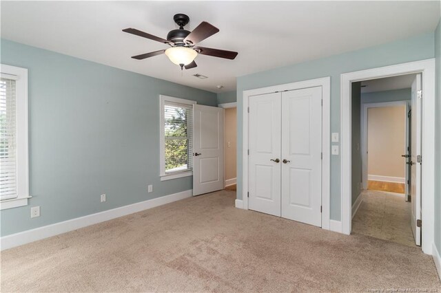 unfurnished bedroom featuring a closet, ceiling fan, and light colored carpet