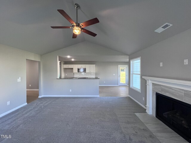 unfurnished living room with lofted ceiling, ceiling fan, a fireplace, and light carpet